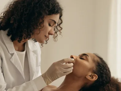 Dermatologista tratando a pele de uma paciente de cabelo cacheado
