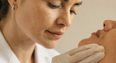 Profissional de luvas examinando a pele de uma paciente
