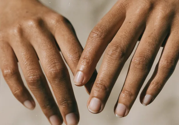 Mulher tocando o próprio rosto com as duas mãos